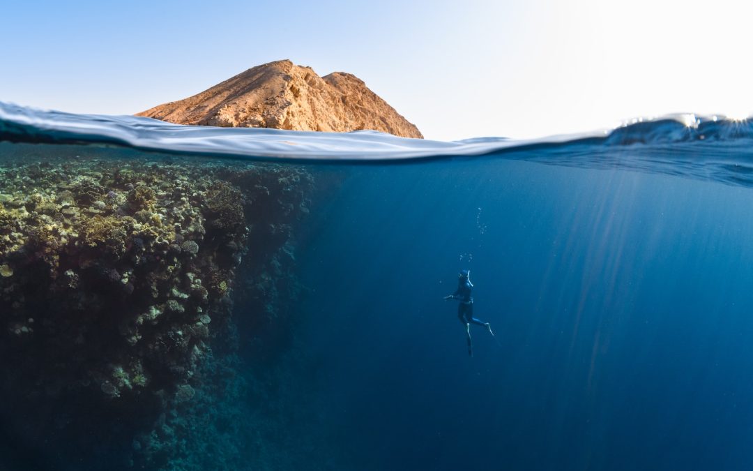 a person swimming in the ocean with a mountain in the background